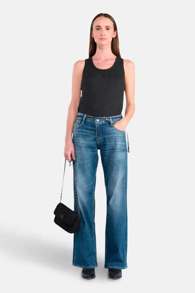 Jean large en denim bleu moyen de Le Temps des Cerises, porté avec un débardeur noir et un sac à main noir à chaîne.