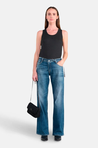 Wijde spijkerbroek in middieblauw denim van Le Temps des Cerises, gedragen met een zwarte tanktop en een zwarte handtas met ketting.