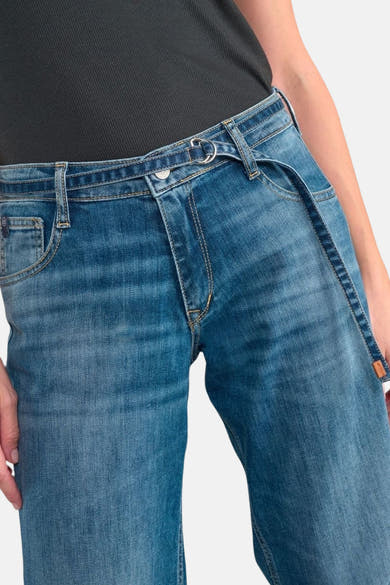 Jean large bleu denim par Le Temps des Cerises, avec ceinture intégrée et détails de couture contrastés.
