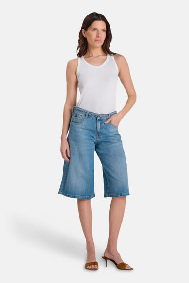 Bermuda en denim bleu moyen de Le Temps des Cerises, porté avec un débardeur blanc et des mules marron.