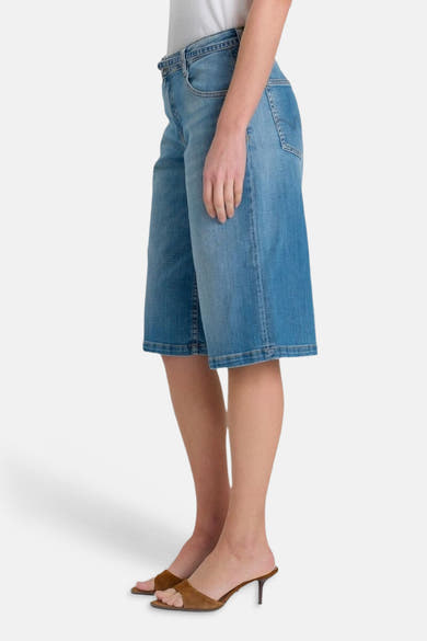 Bermuda mi-mollet en denim bleu moyen de Le Temps des Cerises, avec ourlet fini et coupe ample, en vue latérale.