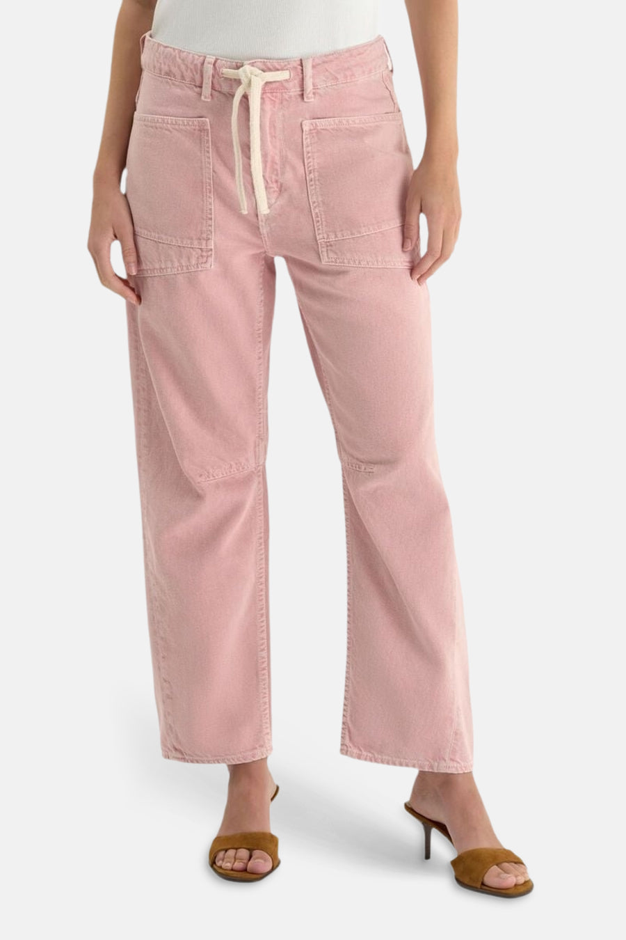 Jean coloré rose par Le Temps des Cerises, avec poches cargo et cordon de serrage, porté avec des mules marron.
