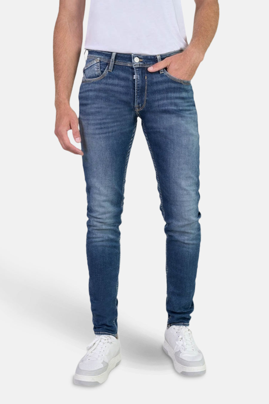 Jean slim en denim bleu foncé de Le Temps des Cerises, porté avec un t-shirt blanc et des baskets blanches.
