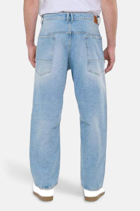 Wijde spijkerbroek in lichtblauw denim van Le Temps des Cerises, met vierkante achterzakken en witte schoenen.