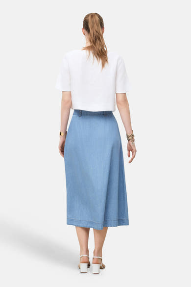 Jupe 3/4 en denim bleu clair de CAROLL, avec une ceinture ajustée et des ourlets bruts.