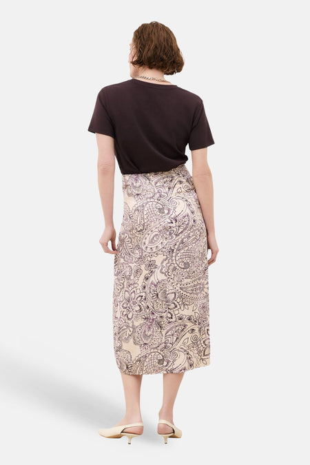 Jupe trois-quarts multicolore de Caroll, à motif cachemire sur fond crème, portée avec un t-shirt marron et des escarpins beiges.