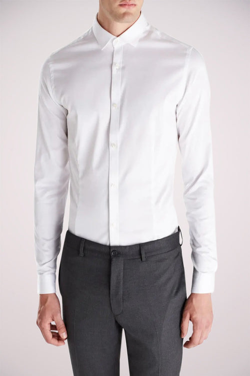 Chemise blanche à manches longues de PREMIUM by JACK & JONES, portée avec un pantalon gris foncé.
