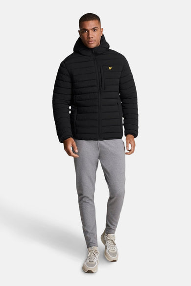 Zwarte regenjas van LYLE & SCOTT, met capuchon en ritssluiting, gedragen met een grijze joggingbroek.