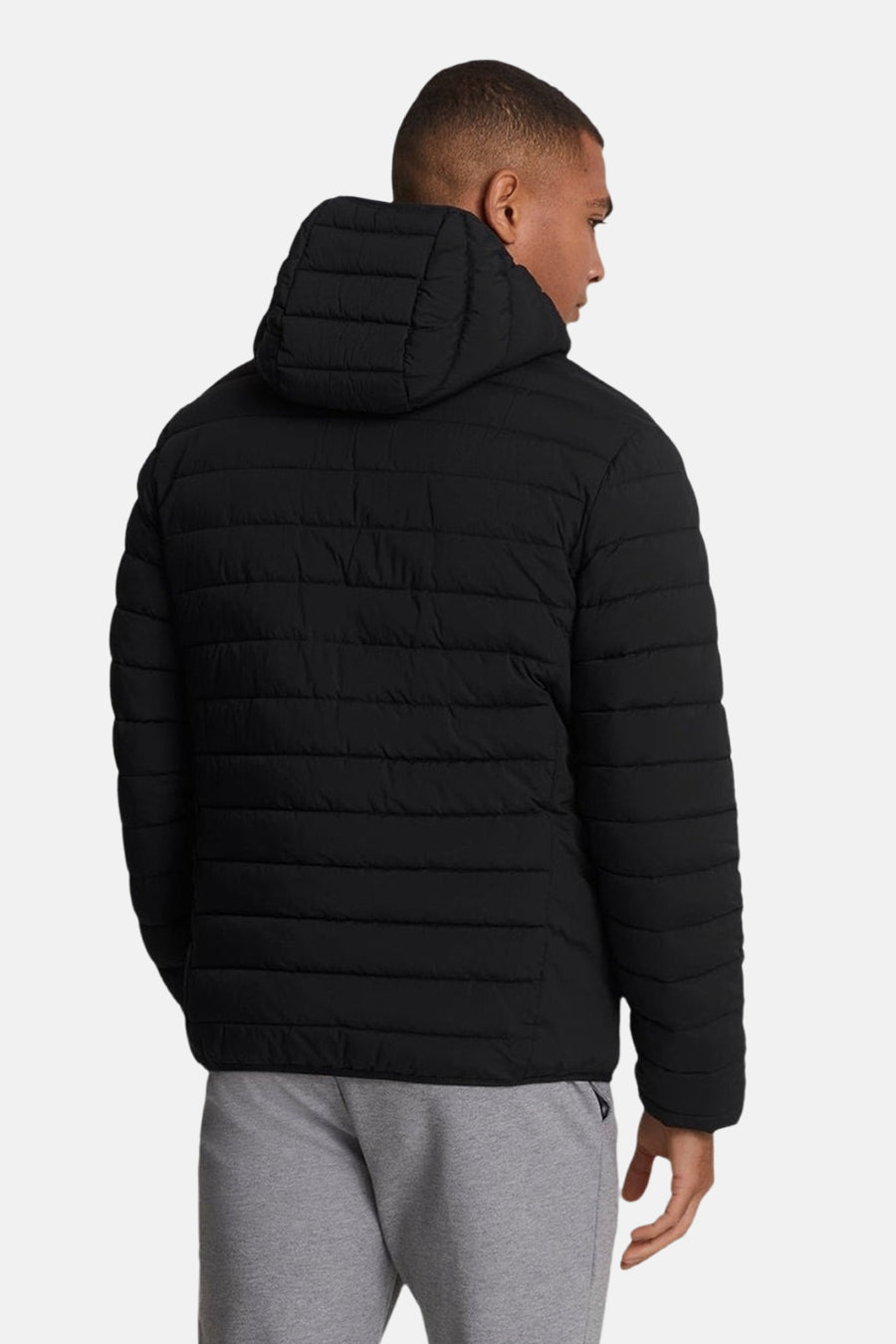 Veste de pluie noire de LYLE & SCOTT, vue de dos, avec capuche et sur un pantalon de survêtement gris.