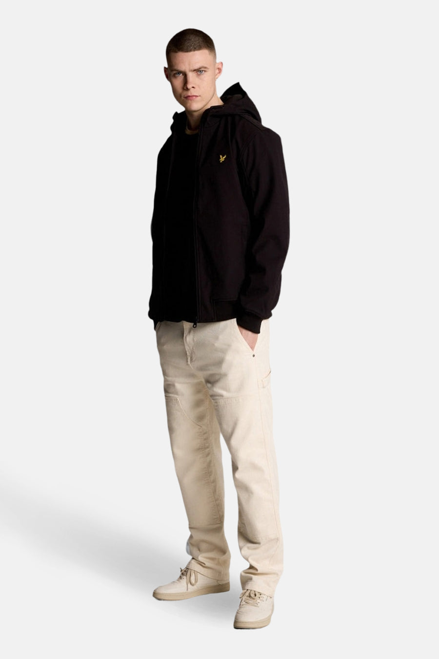 Veste de pluie noire de LYLE & SCOTT, portée avec un pantalon beige et des chaussures assorties.