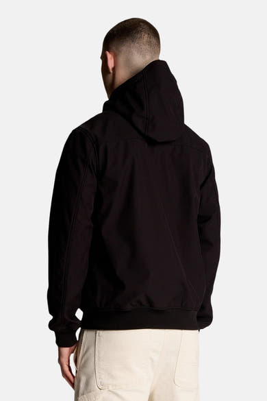 Veste de pluie noire de LYLE & SCOTT, avec capuche, vue de dos, portée avec un pantalon clair.
