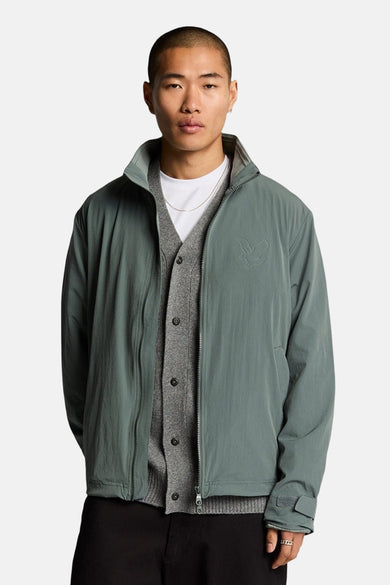 Kaki regenjas van Lyle & Scott met ton-sur-ton logo gedragen over een grijze cardigan.