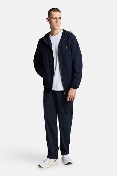 Blauwe regenjas van LYLE & SCOTT, gedragen met een wit T-shirt en een blauwe joggingbroek.