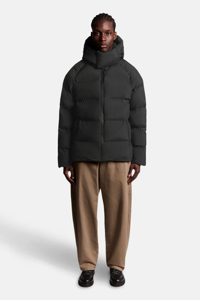 Zwarte regenjas van LYLE & SCOTT, met capuchon, gedragen met een bruine broek en zwarte schoenen.