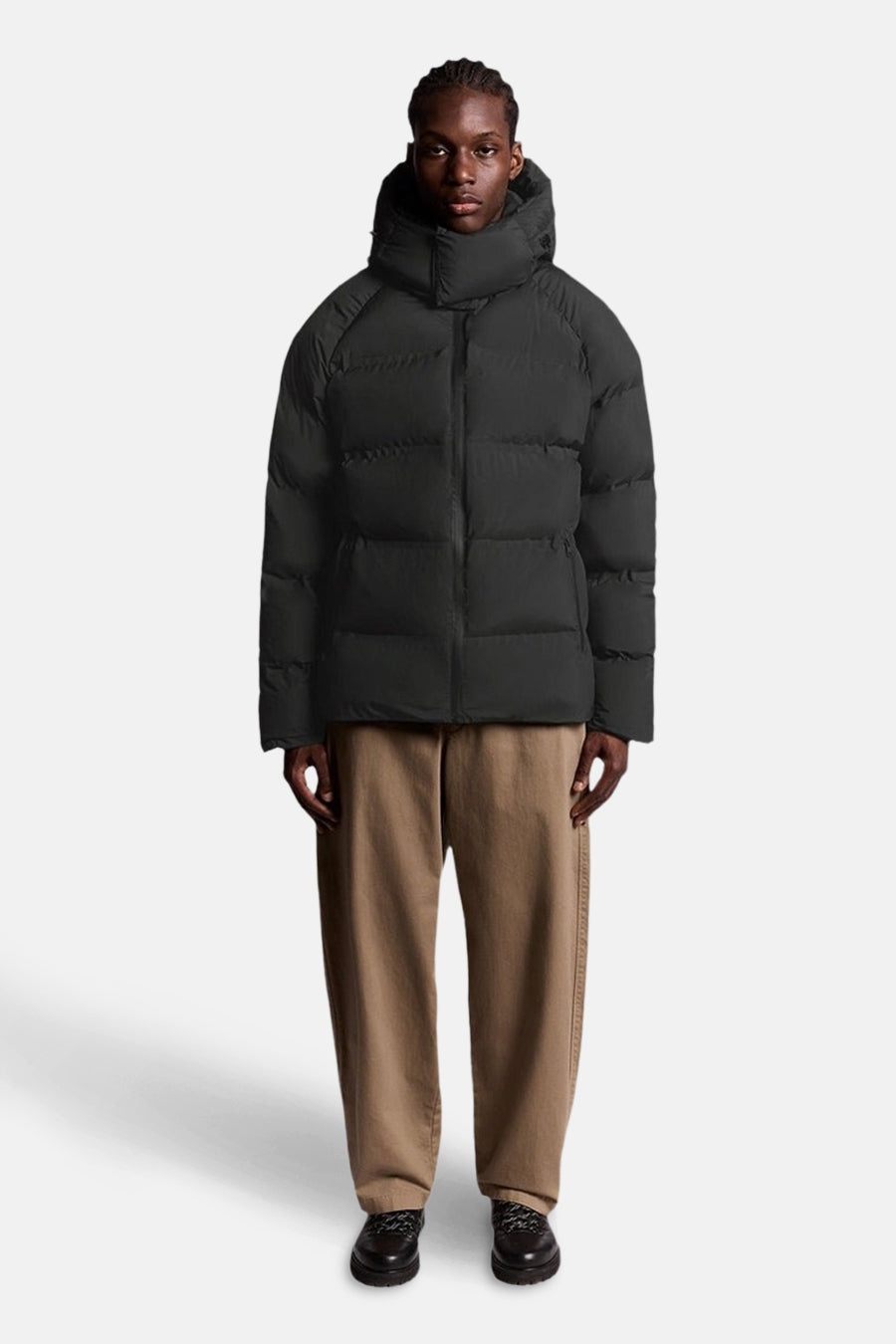 Zwarte regenjas van LYLE & SCOTT, met capuchon, gedragen met een bruine broek en zwarte schoenen.