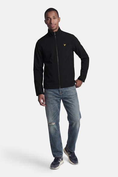 Veste de pluie noire de LYLE & SCOTT portée avec un jean déchiré et des baskets.