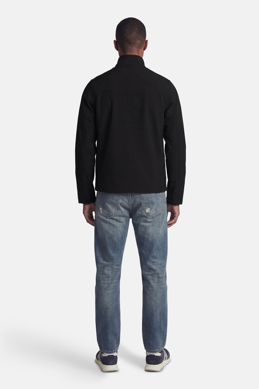 Veste de pluie noire de LYLE & SCOTT, portée avec un jean bleu délavé et des chaussures de sport.