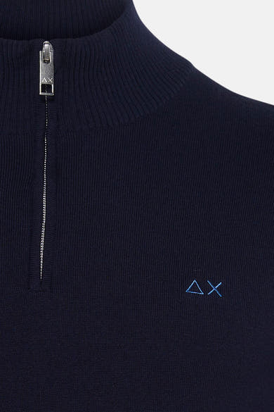 Navy blue ribbed turtleneck sweater with silver zipper and small embroidered logo on chest, close-up front view