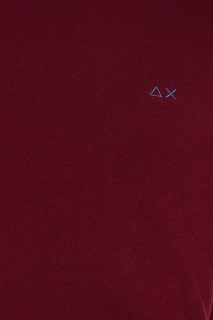 Red O-neck sweater with fine knit texture and small blue embroidered logo on chest, close-up view