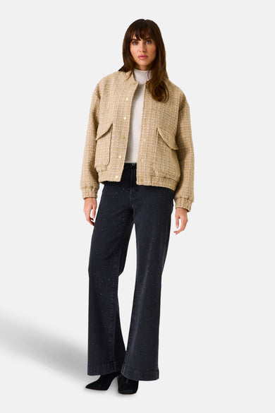 Korte beige tweedjas van GARCIA, met klepzakken, gedragen over een trui en een uitlopende jeans.