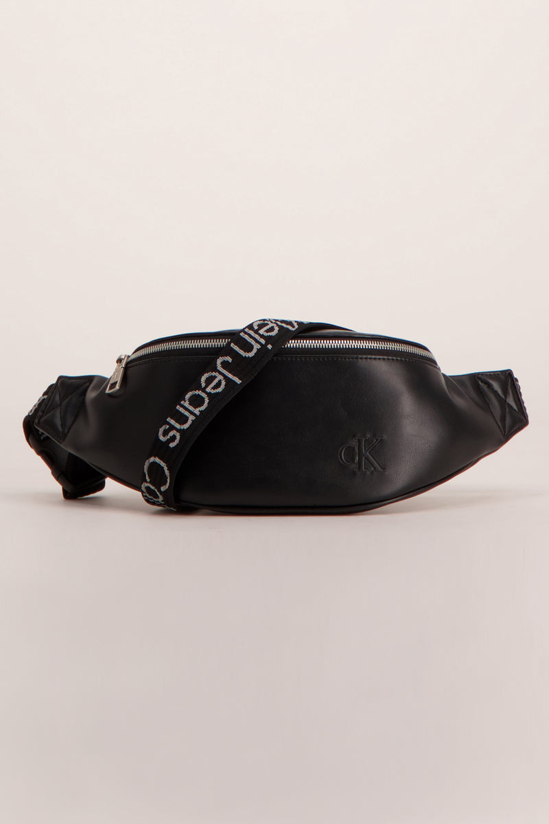Sac banane noir en similicuir de Calvin Klein, avec une bandoulière portant l'inscription de la marque.
