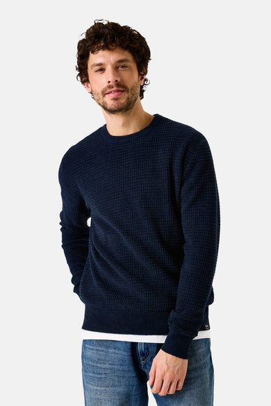 Blauwe rondehals trui van GARCIA met wafelstructuur, gedragen over een wit T-shirt en een blauwe jeans.