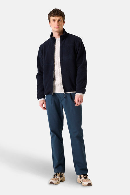 Blauwe fleece van GARCIA, gedragen over een crèmekleurige trui en een bijpassende broek met beige sneakers.