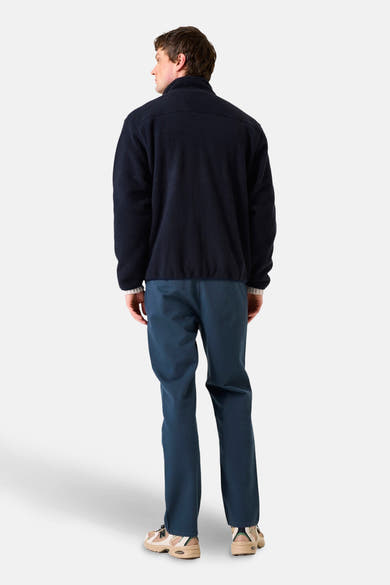 Blauwe fleecejas van GARCIA, van achteren gezien, gedragen met een blauwe broek en beige sneakers.