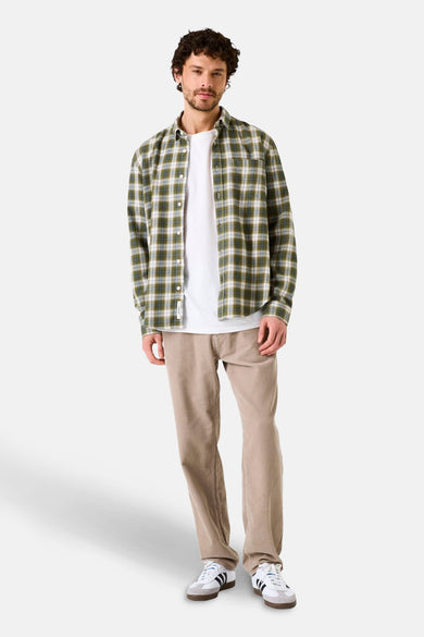 Chemise à manches longues kaki by GARCIA, à carreaux sur un t-shirt blanc et un pantalon beige en velours côtelé.