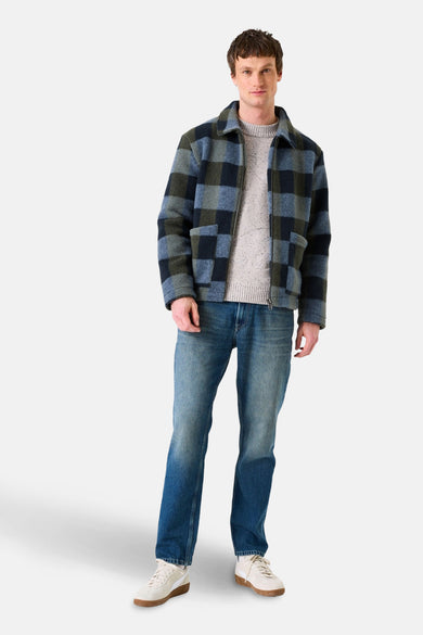 Veste en denim bleu moyen de GARCIA, portée sur un pull en maille, avec un jean bleu et des baskets blanches.