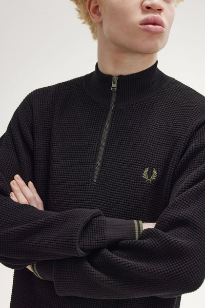 Pull noir à col montant de Fred Perry avec fermeture éclair et motif gaufré.