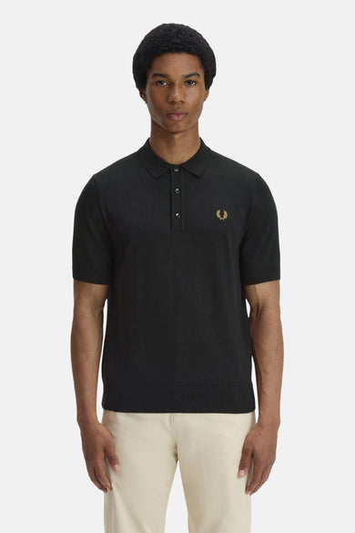 Zwarte polo van FRED PERRY, versierd met het kenmerkende logo, gedragen met een casual beige broek.