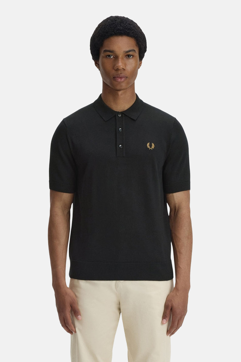 Zwarte polo van FRED PERRY, versierd met het kenmerkende logo, gedragen met een casual beige broek.
