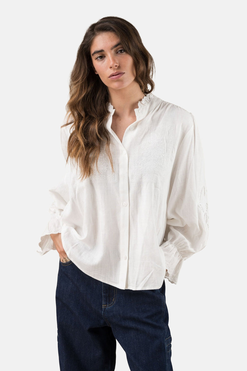 Wit overhemd met lange mouwen van ADORE, versierd met borduursels en gedragen met een donkerblauwe jeans.