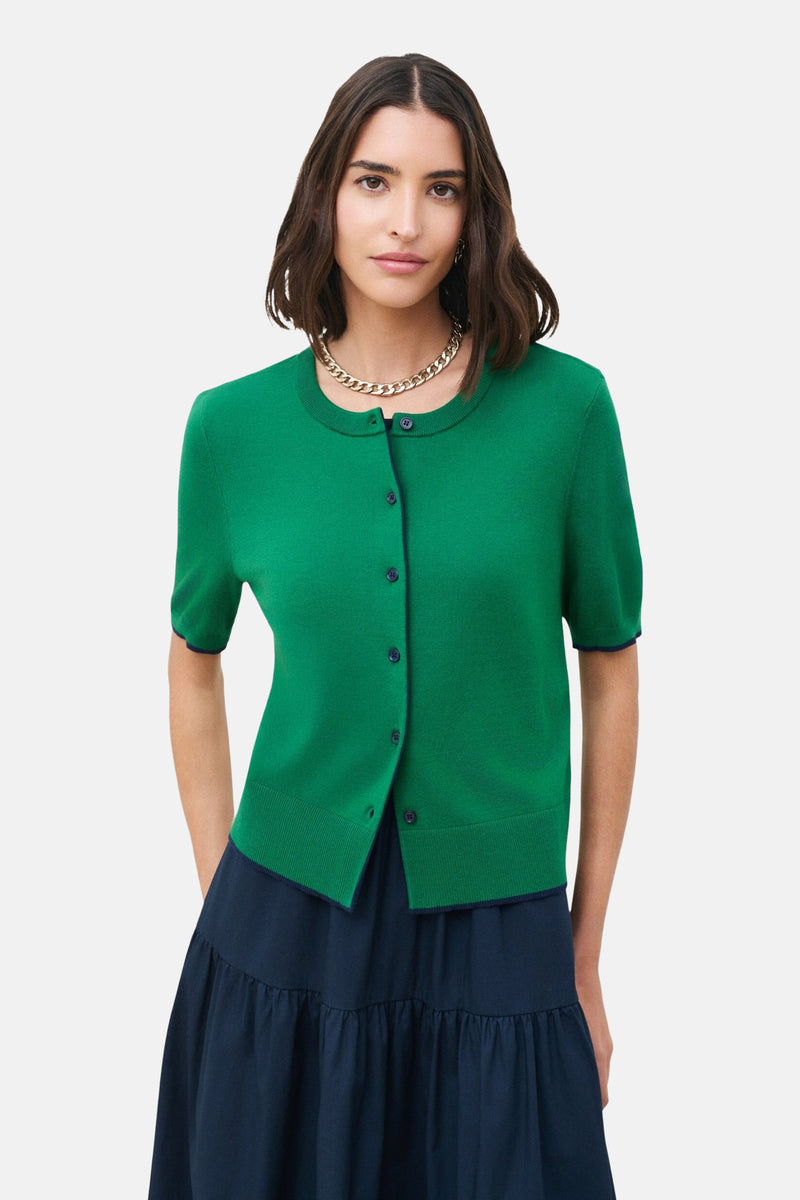 Emeraldgroene cardigan van CAROLL, korte mouwen, gedragen met een marineblauwe geplooide midirok.