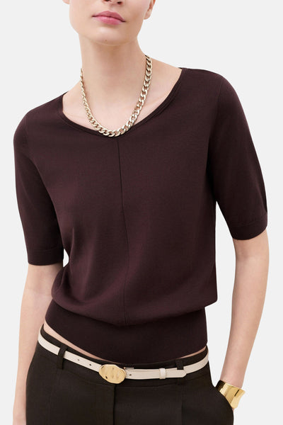 Pull col rond brun en maille fine de CAROLL à manches courtes, porté avec un collier chaîne doré.