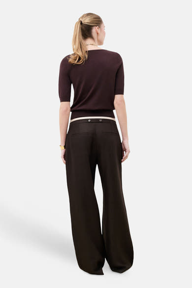Pull col rond brun de CAROLL à manches courtes, porté au dos avec un pantalon large brun et une ceinture claire.
