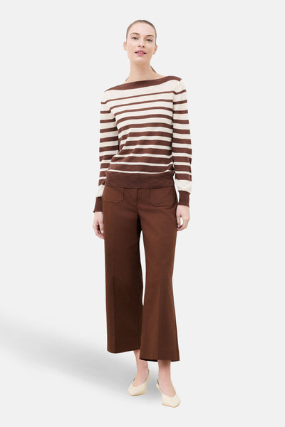 Pull à col rond multicolore de CAROLL, à rayures marron et beige, porté avec un pantalon marron ample.