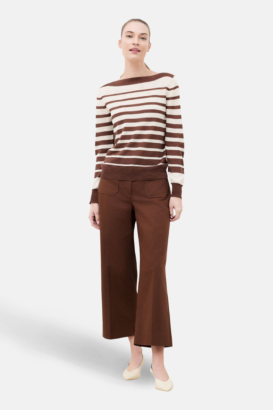 Pull à col rond multicolore de CAROLL, à rayures horizontales marron et crème, porté avec un pantalon marron.