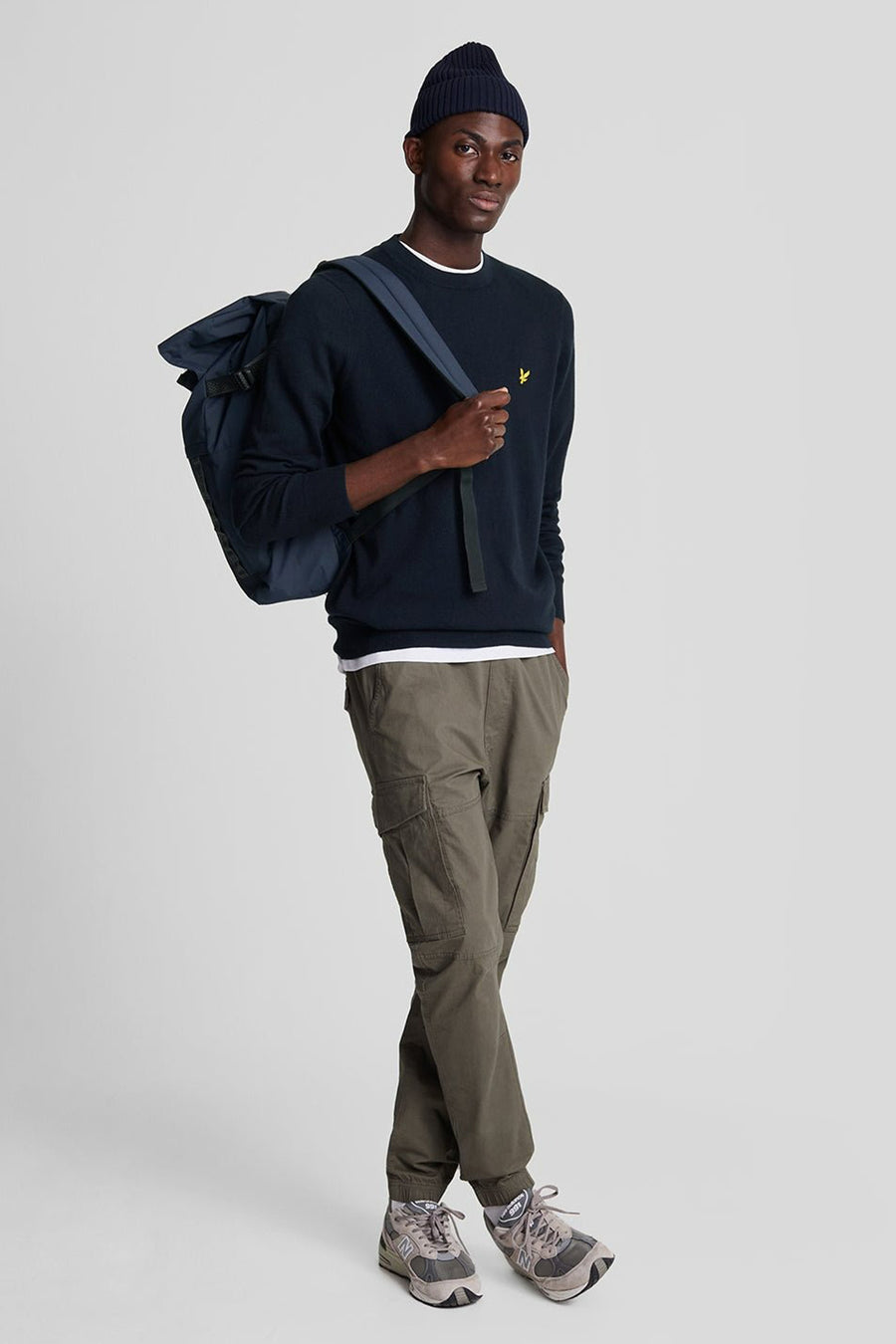 Ronde hals trui blauw van LYLE & SCOTT, gedragen met een kaki cargobroek en een marineblauwe muts.