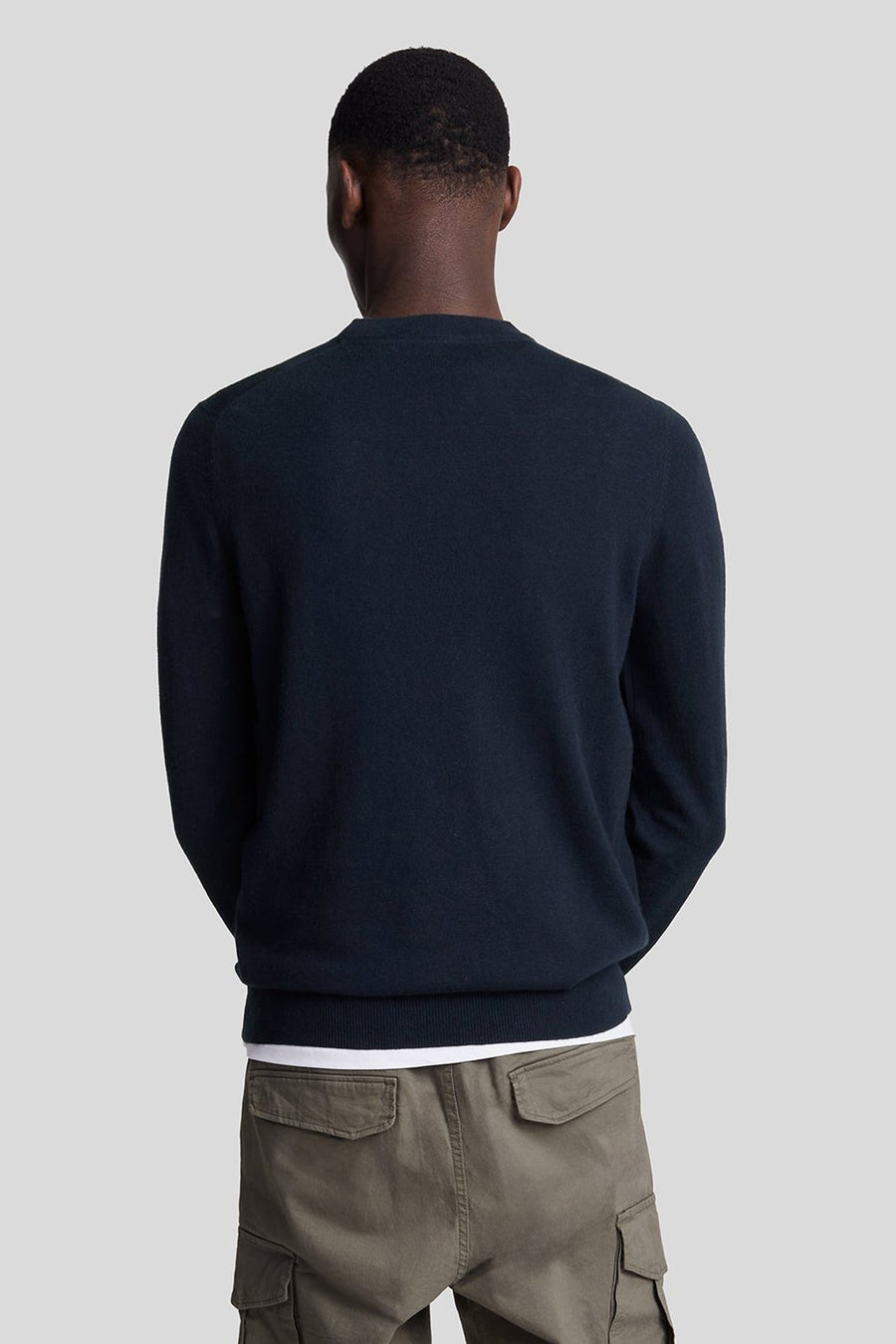 Pull à col rond bleu de LYLE & SCOTT, porté avec un pantalon cargo olive, vue de dos.