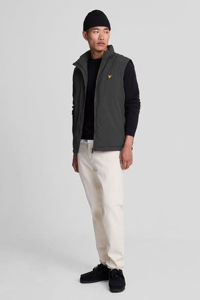 Pull à col rond noir de LYLE & SCOTT, porté avec un gilet sans manches et un bonnet.