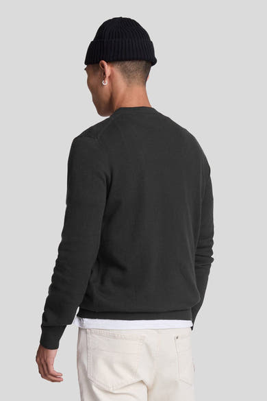 Pull ras du cou noir de LYLE & SCOTT, porté avec un bonnet et un jean clair, vue de dos.