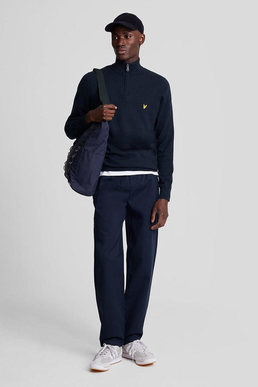 Pull à col roulé bleu marine de Lyle & Scott, porté avec un pantalon bleu marine et des chaussures de sport grises.
