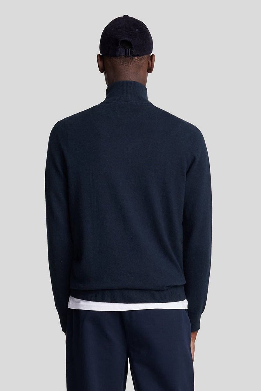 Pull à col roulé bleu par LYLE & SCOTT, porté avec un t-shirt blanc et un pantalon marine, vue de dos.