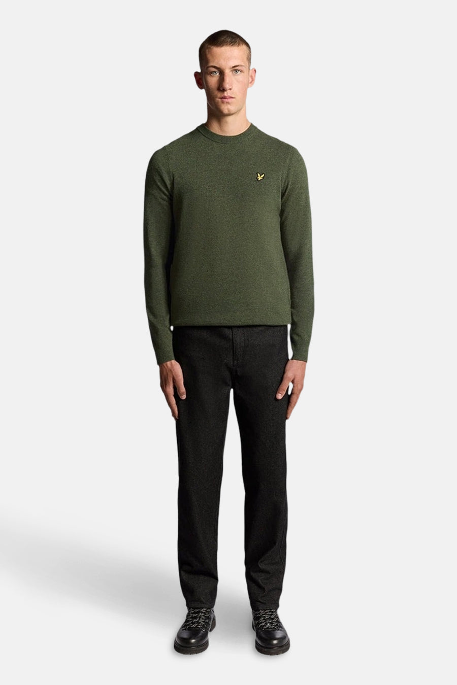 Olijfgroene trui met ronde hals van Lyle & Scott, gedragen met een donkere spijkerbroek en zwarte schoenen.
