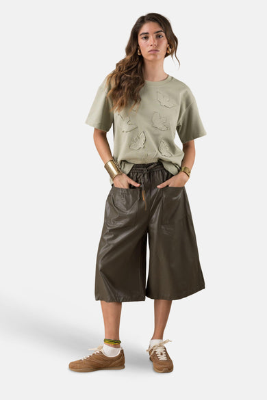 Korte broek, van ADORE, met zakken en trekkoord, gedragen met een T-shirt, armbanden en sportschoenen.