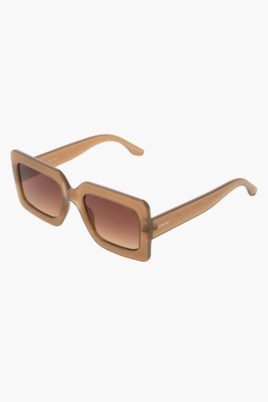 Lunettes de soleil beiges de KOMONO, avec verres dégradés marron, présentées de biais.