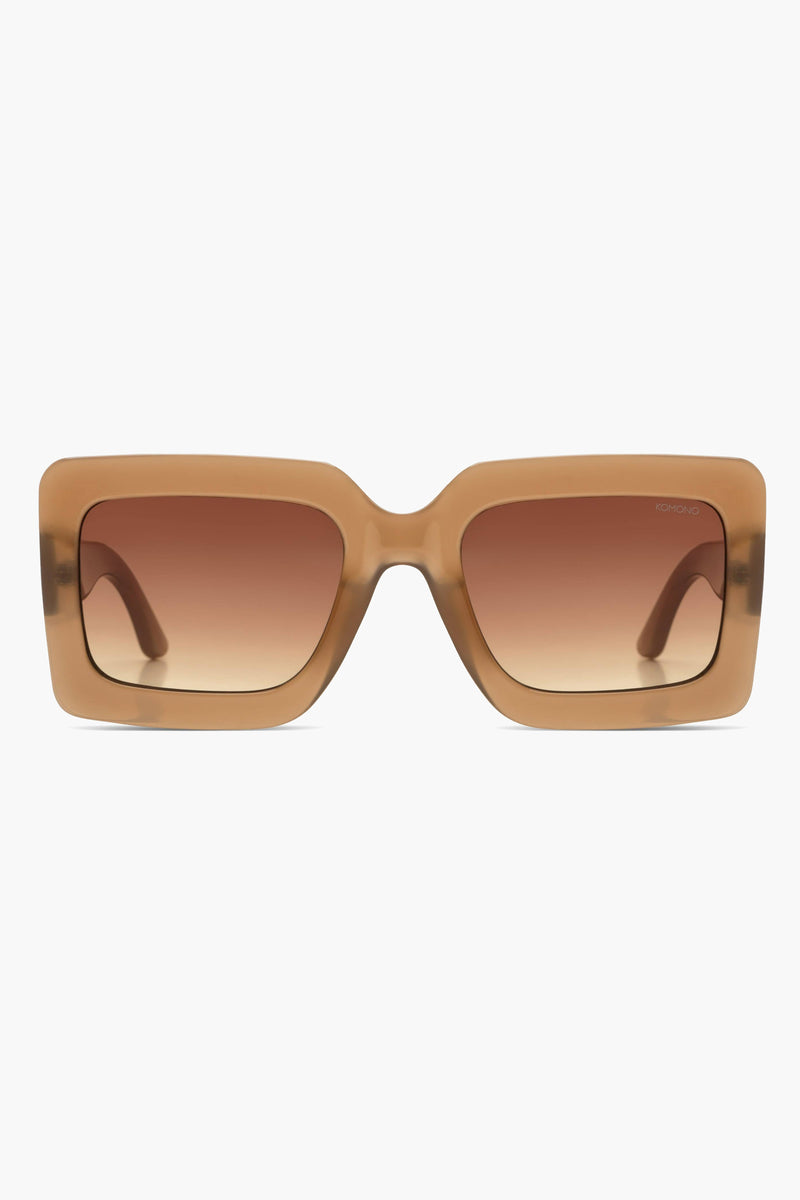 Lunettes de soleil beiges de Komono, avec des verres dégradés marron clair à marron foncé.