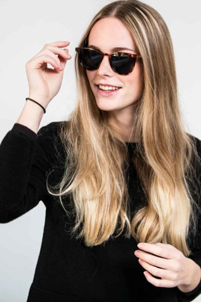 Groene zonnebril van KOMONO, gedragen door een blonde vrouw met een zwarte trui.